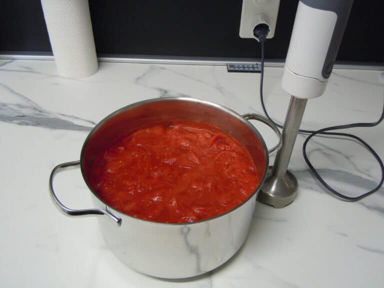 a pan of homemade tomato sauce ready for blending on a white marble kitchen worktop