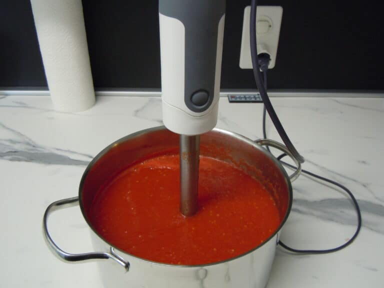 blending homemade tomato sauce with an immersion hand blender