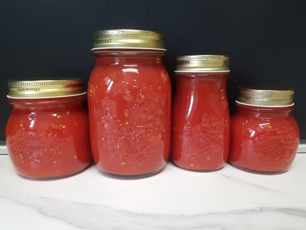 different sized jars of homemade tomato sauce.