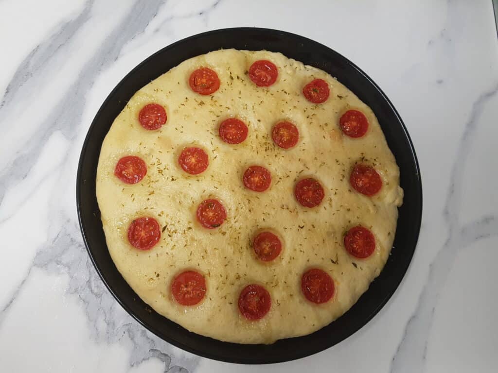 A focaccia with cherry tomatoes and oregano, ready to go in the oven