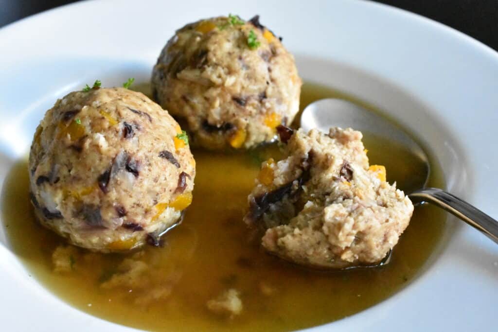 Canederli in vegetable broth in a white bowl