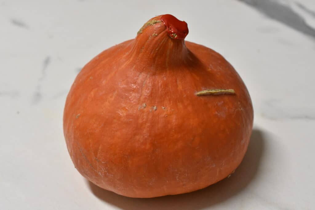 A whole Hokkaido pumpkin, also known as Potimarron or red Kuri squash.