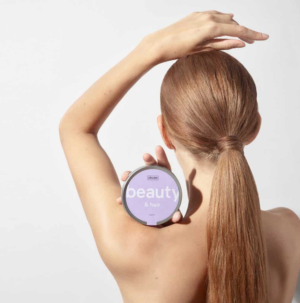 A model holding a tin of Ringana vegan beauty and hair caps.