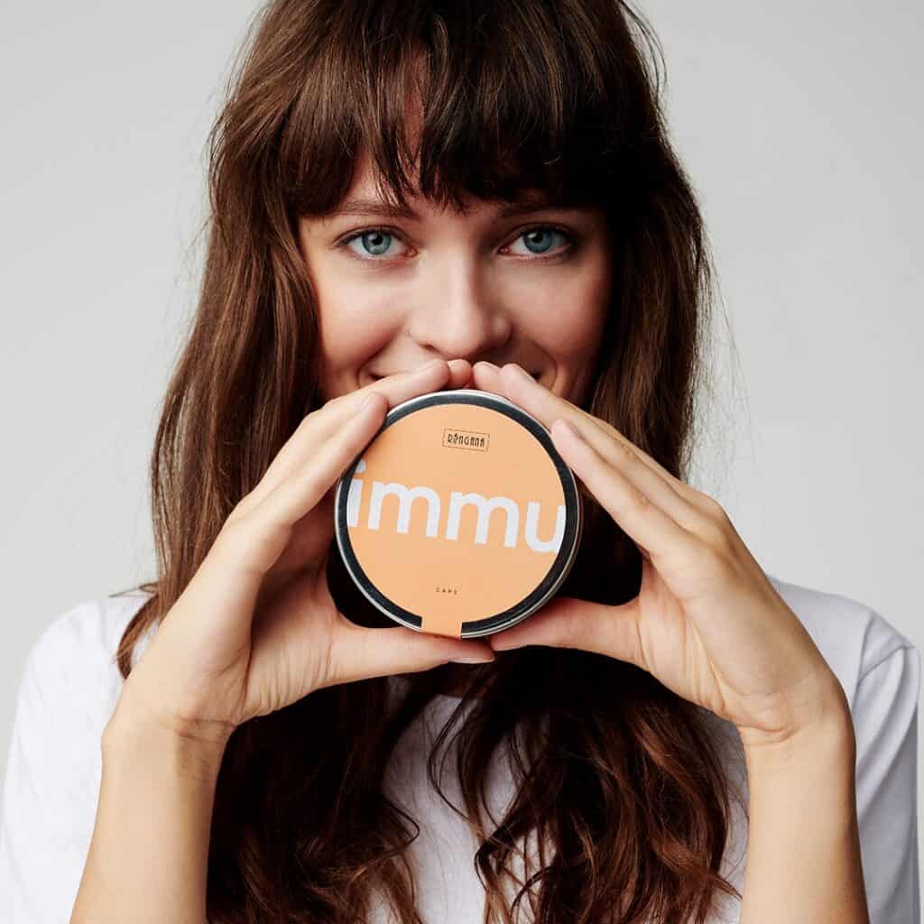 A model holding a tin of Ringana fresh vegan immu caps.