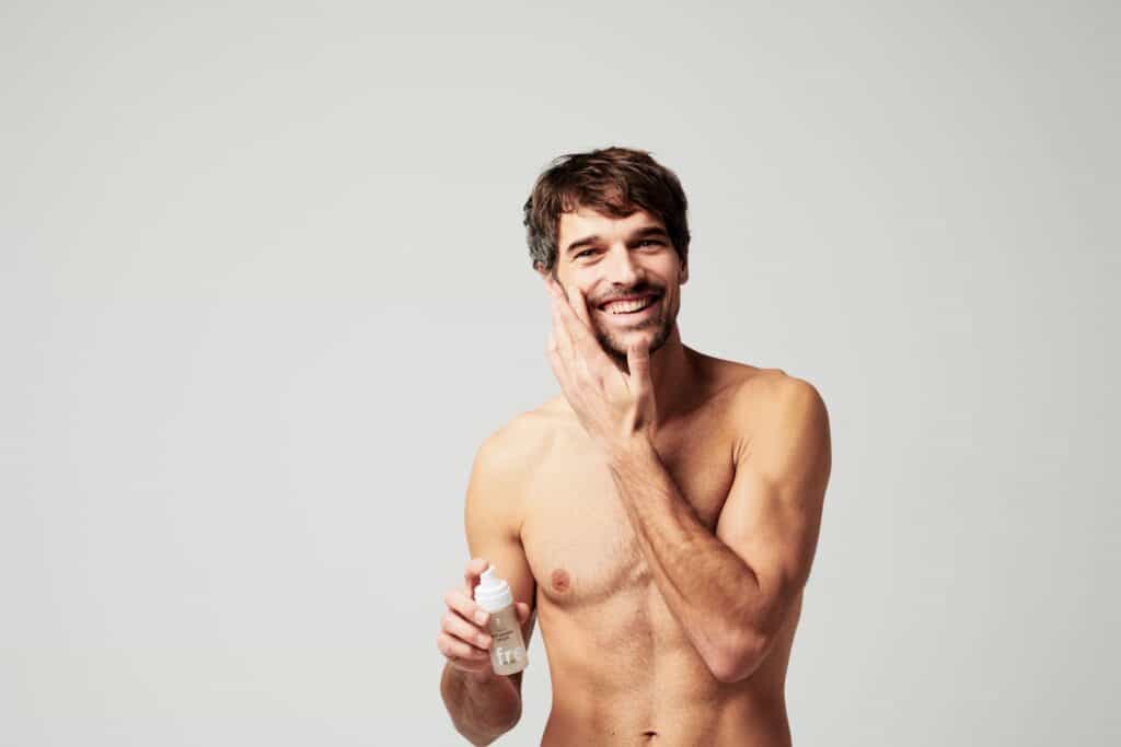 A man holding a bottle of Ringana anti wrinkle serum for men.