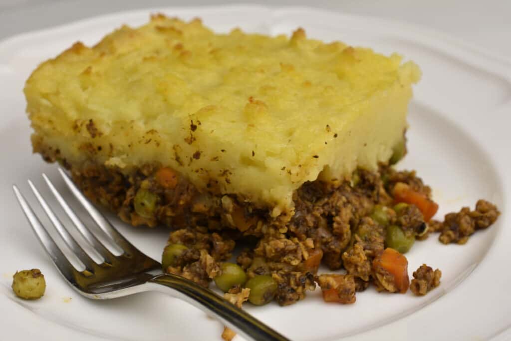 Close up of vegan shepherd's pie on a white plate with a fork