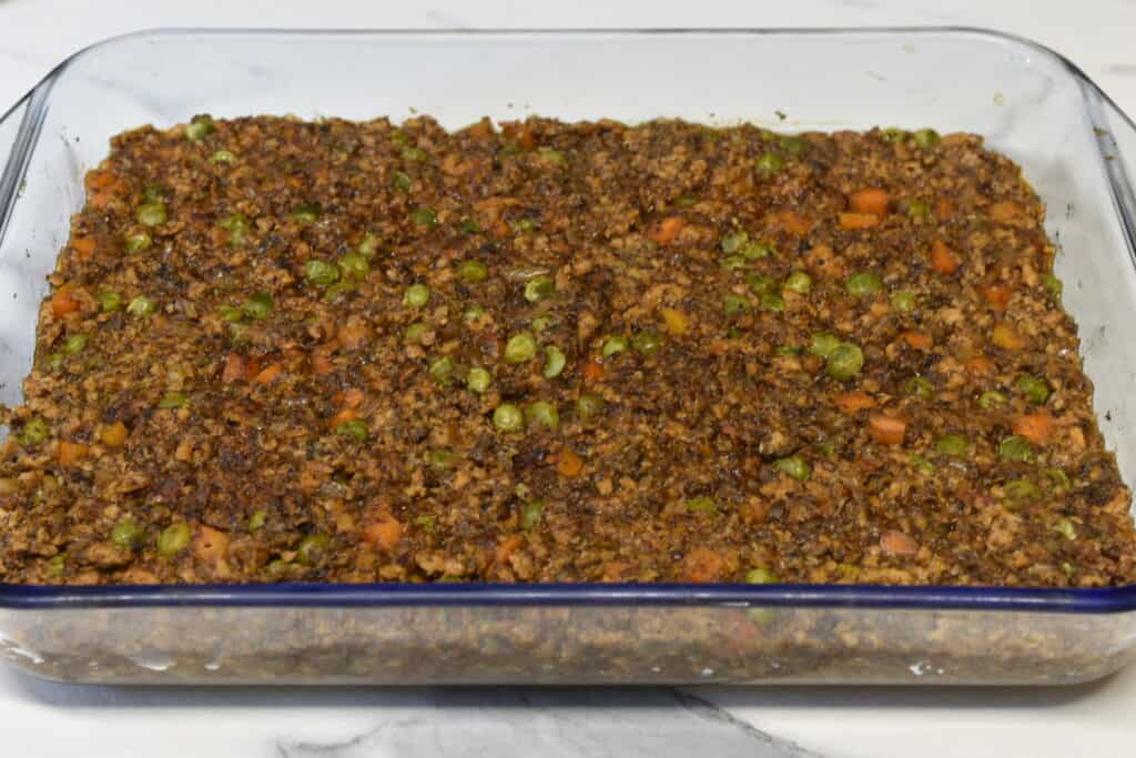 Vegan shepherd's pie filling in a transparent Pyrex oven dish