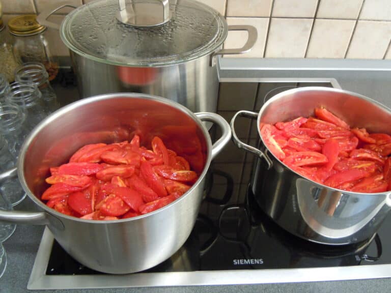 Skinned and quartered Italian plum tomatoes in saucepans on the stove