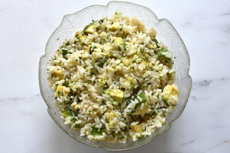 Avocado lime rice in a glass bowl on a worktop.