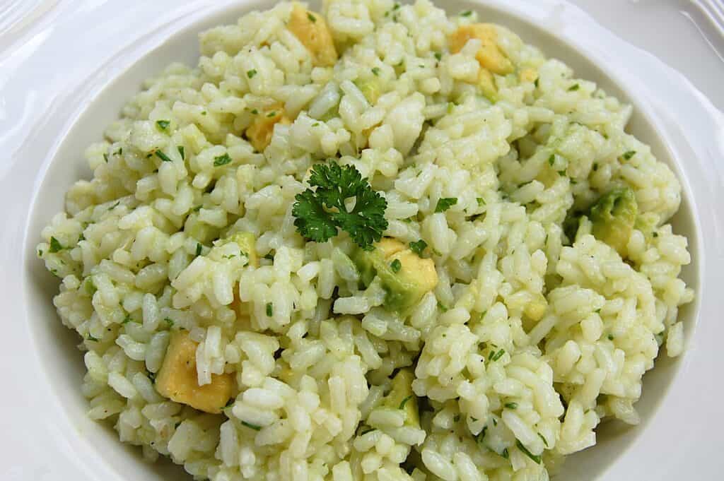 Avocado lime rice on a white plate with a garnish of parsley.