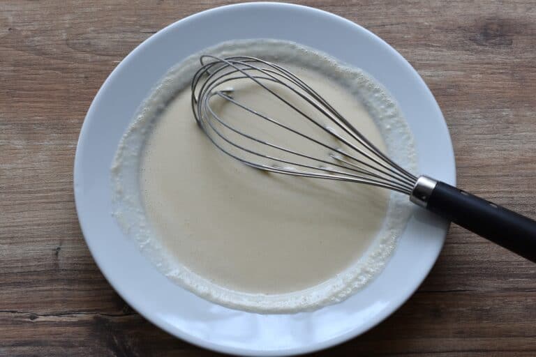 Beer batter in a bowl with a hand whisk.