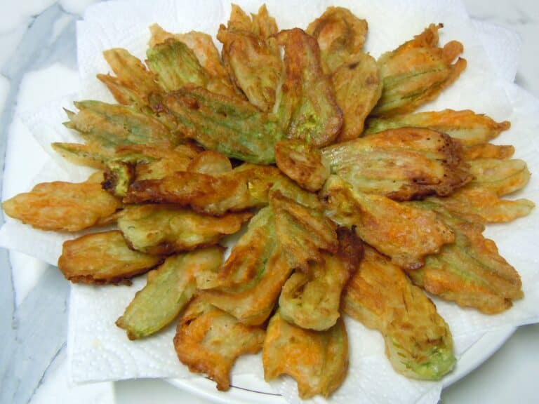 Courgette flowers fried in beer batter on a serving plate.