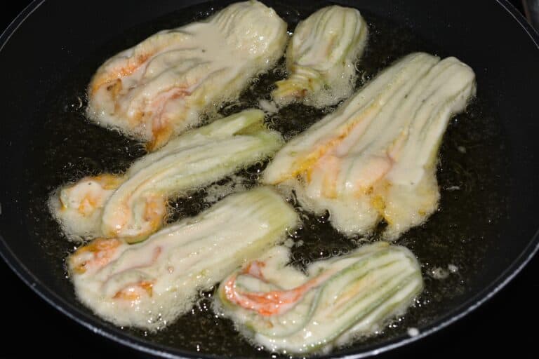 Courgette (zucchini) flowers shallow frying in sunflower oil in a non-stick pan.