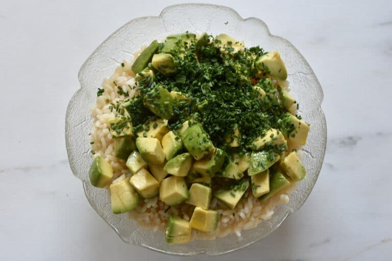 Ribe rice, avocado, lime and lemon juice, and fresh herbs in a glass bowl.