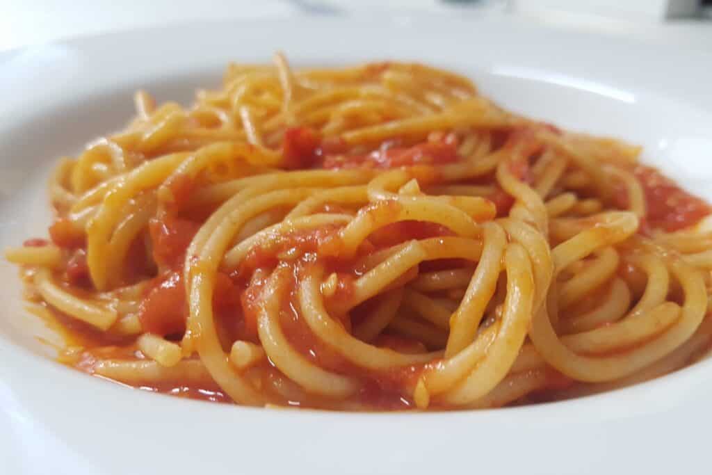 A plate of spaghetti with fresh tomato pasta sauce