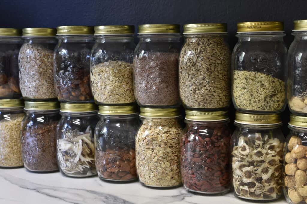 Nuts, cereals, and dried fruit in glass jars with a lid, on a kitchen counter