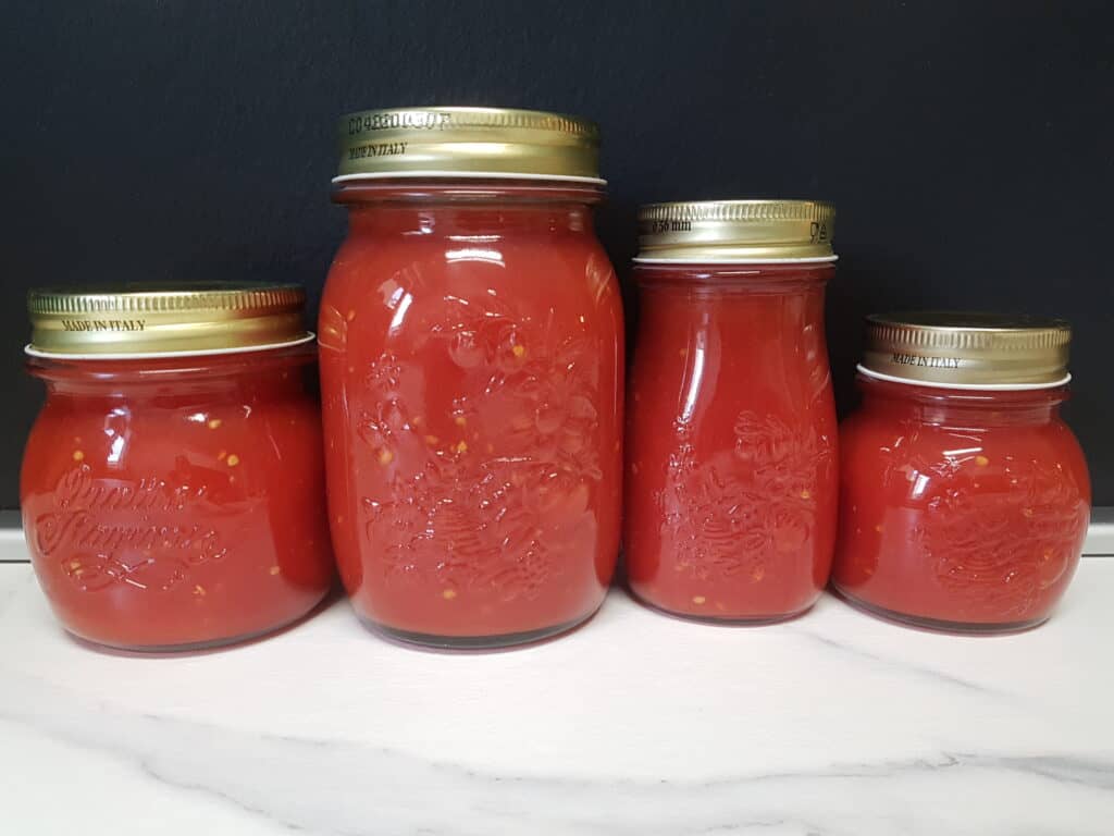 Jars of homemade tomato sauce on a kitchen worktop