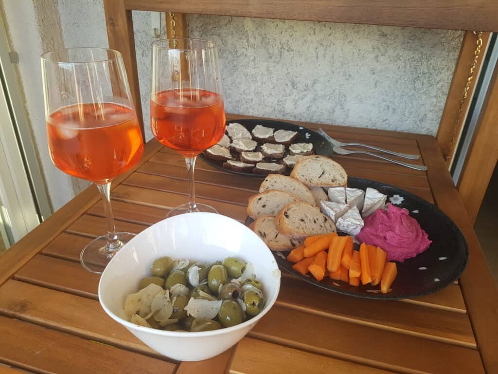 Vegan appetisers and two glasses of Aperol Spritz on a wooden table