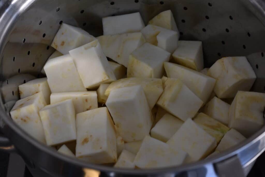 Cubes of raw celeriac in a steamer basket