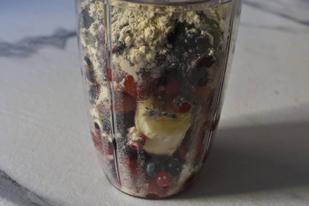 Mixed berries, seeds and protein powder in a blender beaker