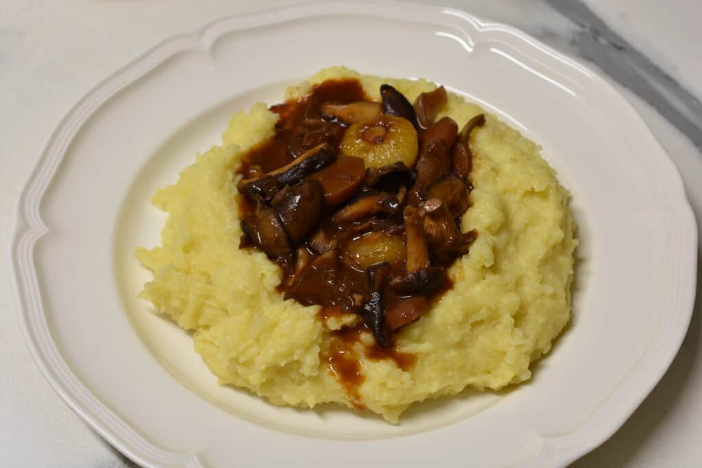 Mushroom bourguignon in a well of mashed potatoes on a white plate