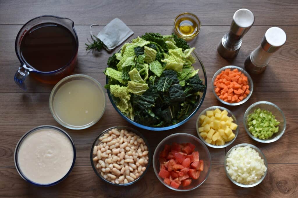 Ingredients for ribollita toscana (Tuscan ribollita or Tuscan bean soup) in individual glass dishes on a table.