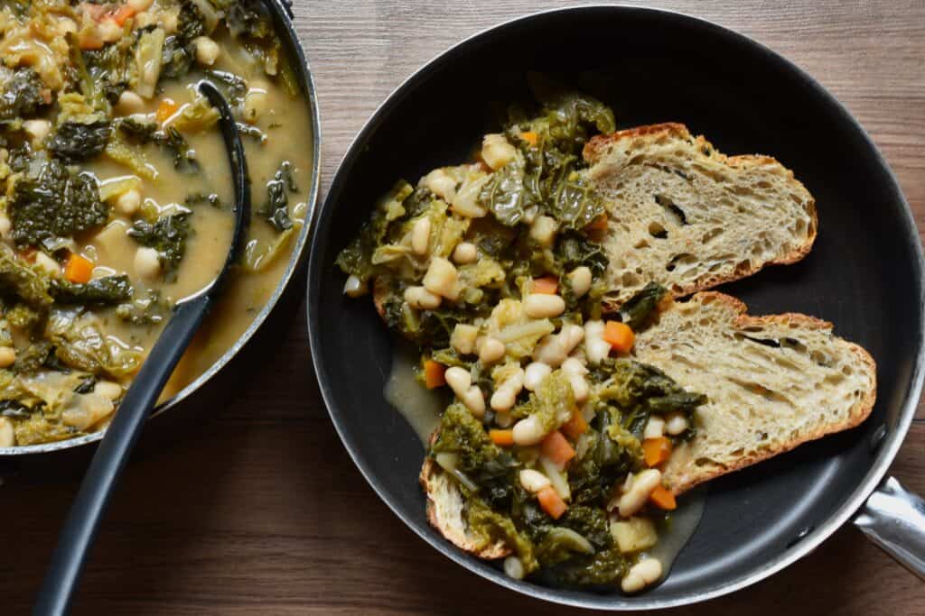 Tuscan ribollita soup (ribollita toscana) and slices of stale bread in pans.