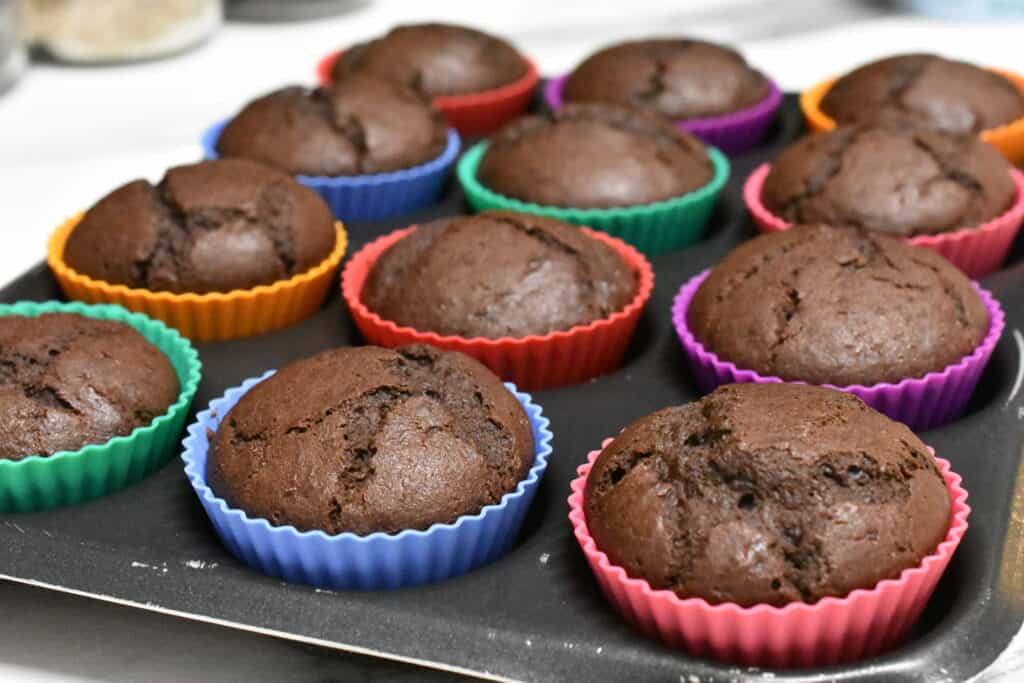 Vegan chocolate muffins in coloured cake cases on a muffin tray