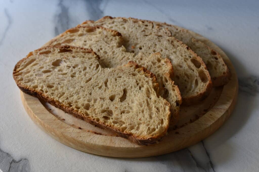 4 slices of sourdough bread on a round wooden chopping board