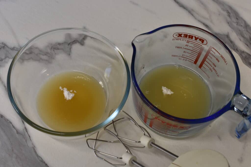 Two glass containers with the cooking liquid from dried chickpeas (left) and tinned chickpeas (right) with cream of tartar