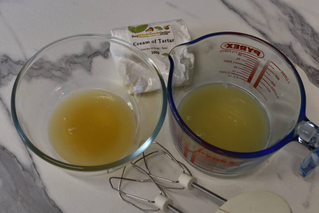 Two glass containers with the cooking liquid from dried chickpeas (left) and tinned chickpeas (right)