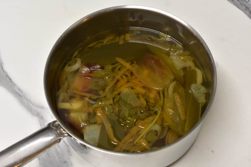 Vegetable broth made from kitchen scraps in a saucepan.