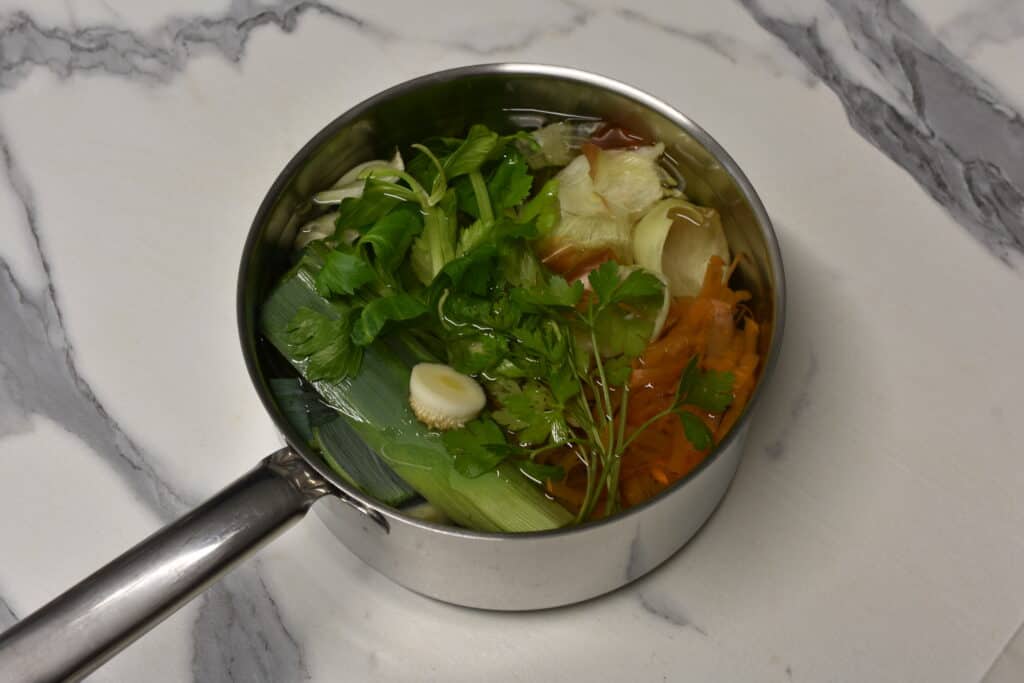 Kitchen scraps for vegetable broth in a saucepan full of cold water.