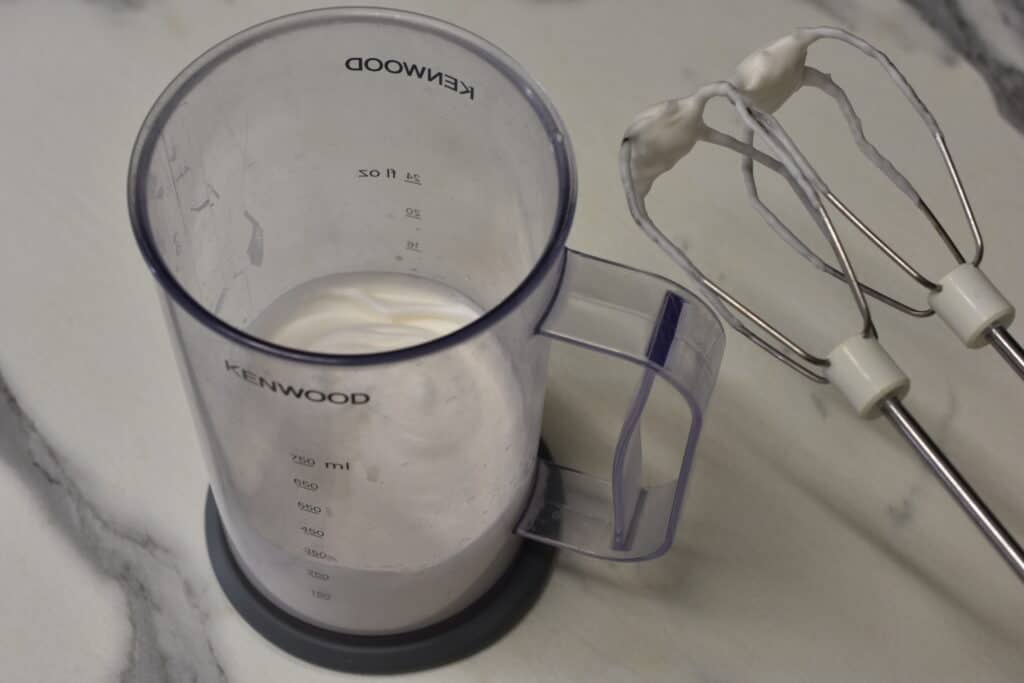 Whipped aquafaba in a transparent plastic measuring jug