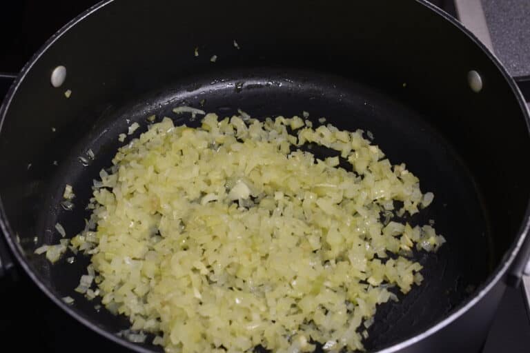 Cooked chopped onions and celery in a pan.