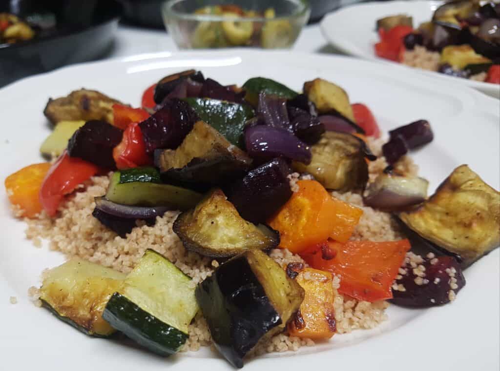 Close-up image of roasted vegetable couscous on a white plate