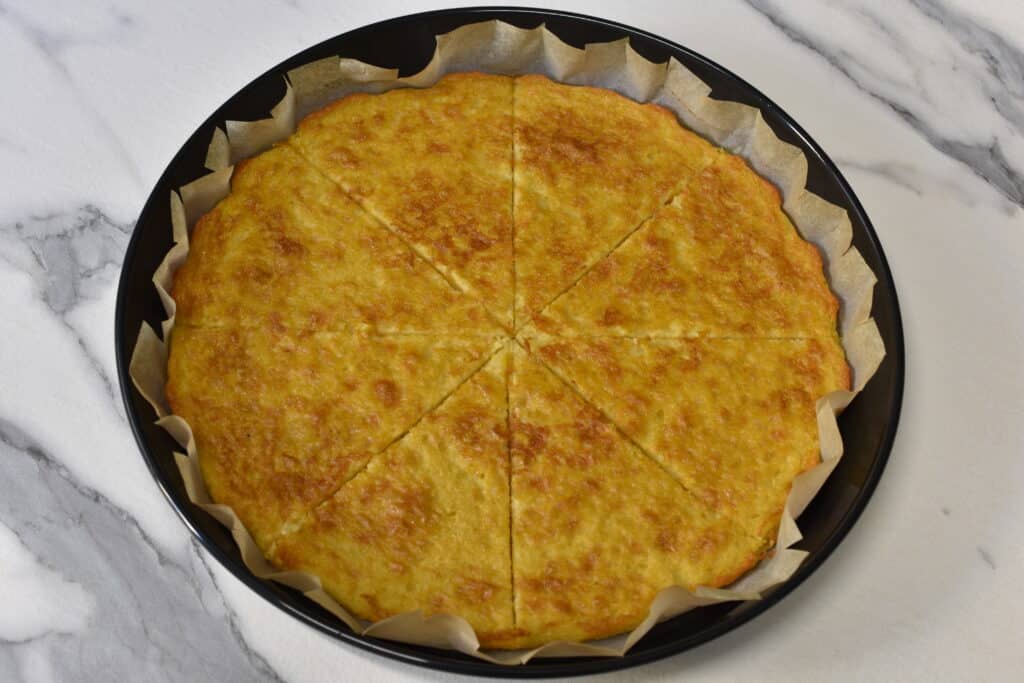 A whole farinata cut into 8 slices in a shallow tin