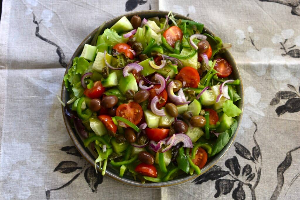 Greek-style mixed salad on a grey plate on a tablecloth