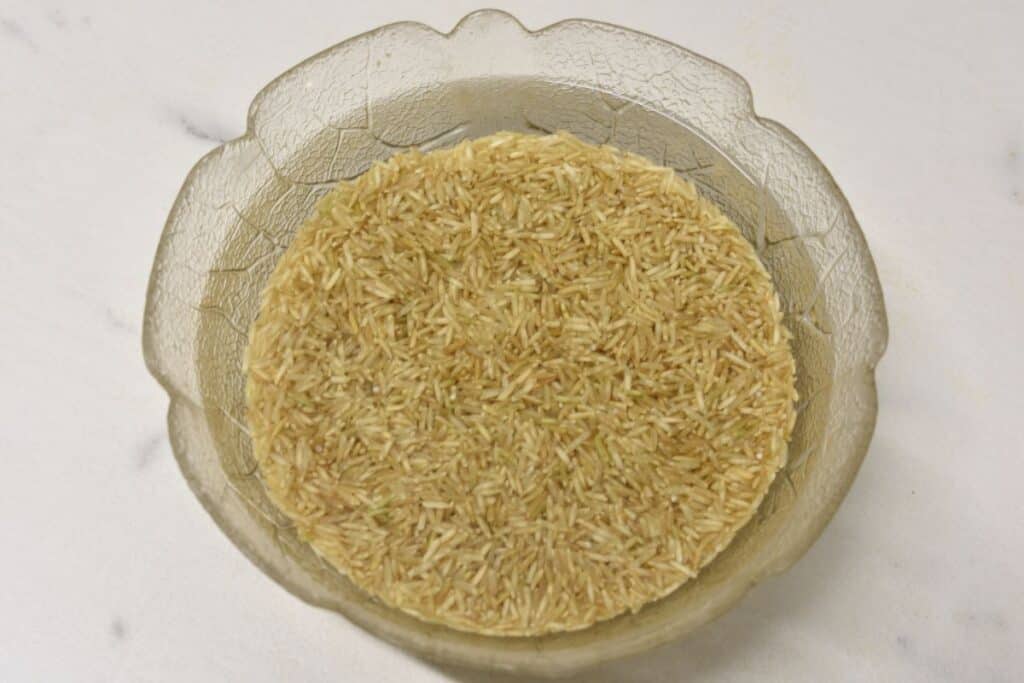 Brown basmati soaking in water in a glass bowl