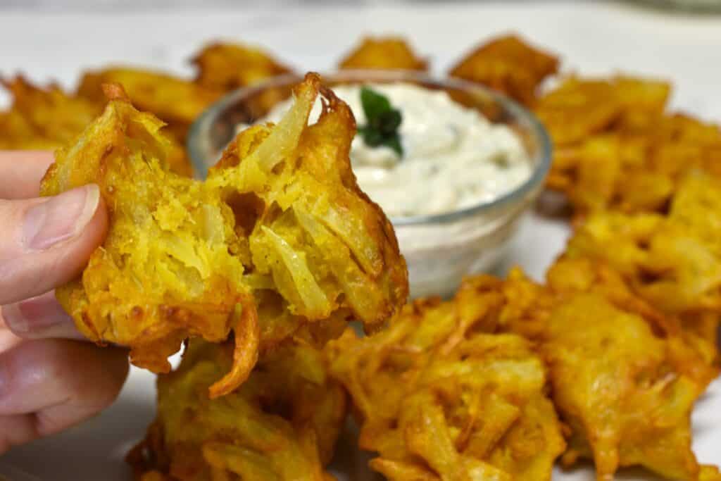 Close-up image of the inside of an onion bhaji with other onion bhaji in the background.