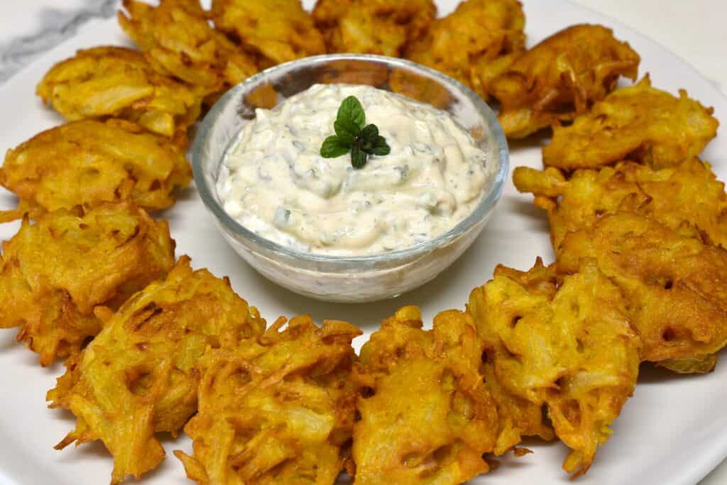 Onion bhaji and cucumber raita on a white plate