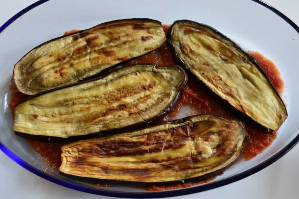 Put a thin layer of tomato sauce in the bottom of the oven dish. Put the first layer of aubergines on top of the tomato sauce.