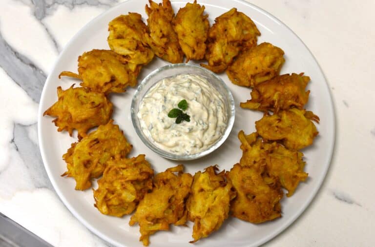 A ring of onion bhaji and a bowl of cucumber mint raita in the centre