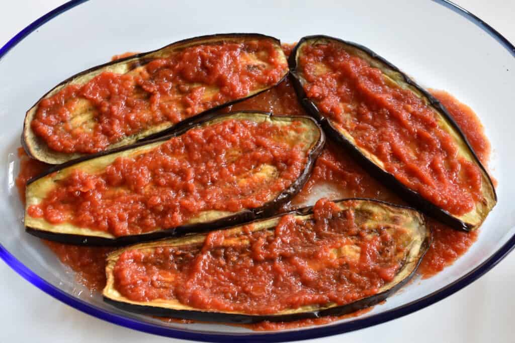 Spread a thin layer of tomato sauce on the slices of aubergines.