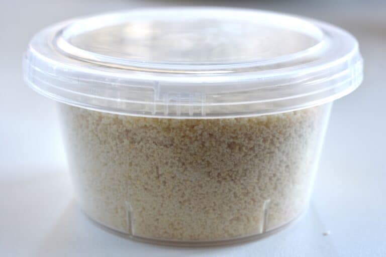 Vegan parmesan cheese in a plastic container with a lid.