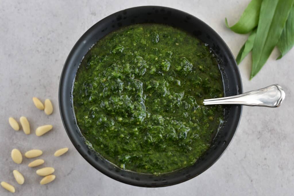 Vegan wild garlic (ramsons) pesto in a black serving bowl with a spoon