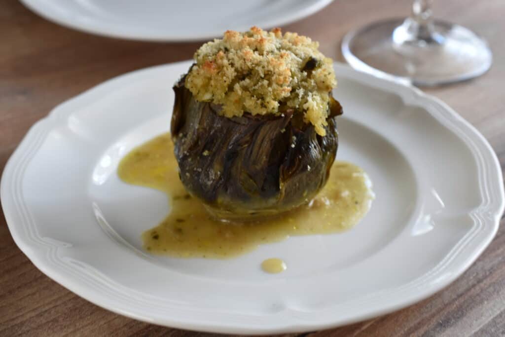 A stuffed artichoke on a white plate.