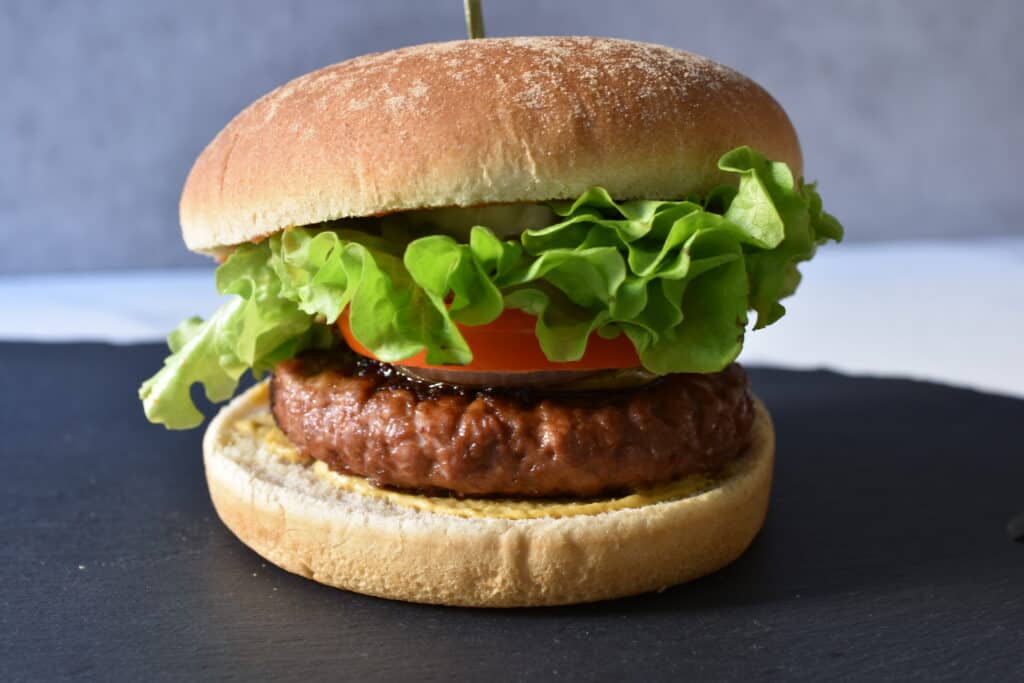 A vegan fast food burger opened slightly to show the ingredients.