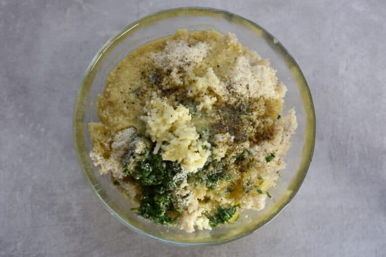 Breadcrumbs, olive oil, parsley, vegan parmesan cheese, garlic, salt, and pepper in a glass bowl.