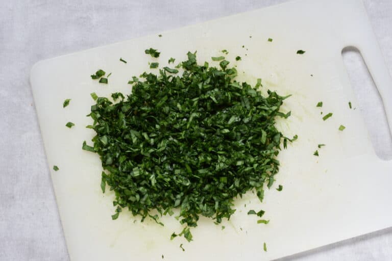 Chopped wild garlic on a white chopping board.